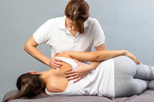 Female therapist manipulating shoulder