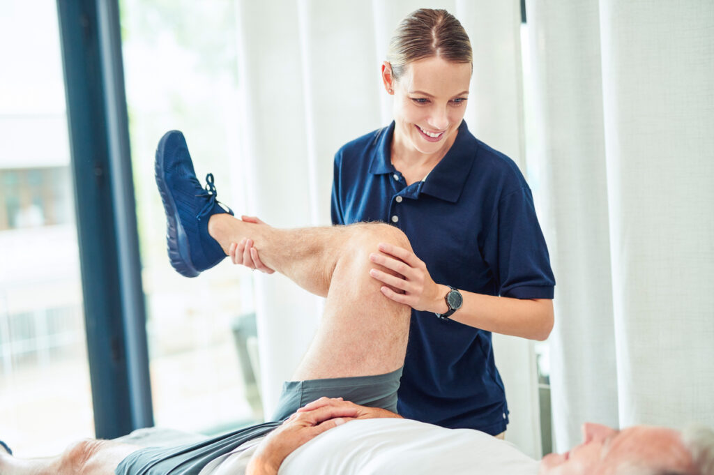 worker's camp Doctor moving leg of elderly man