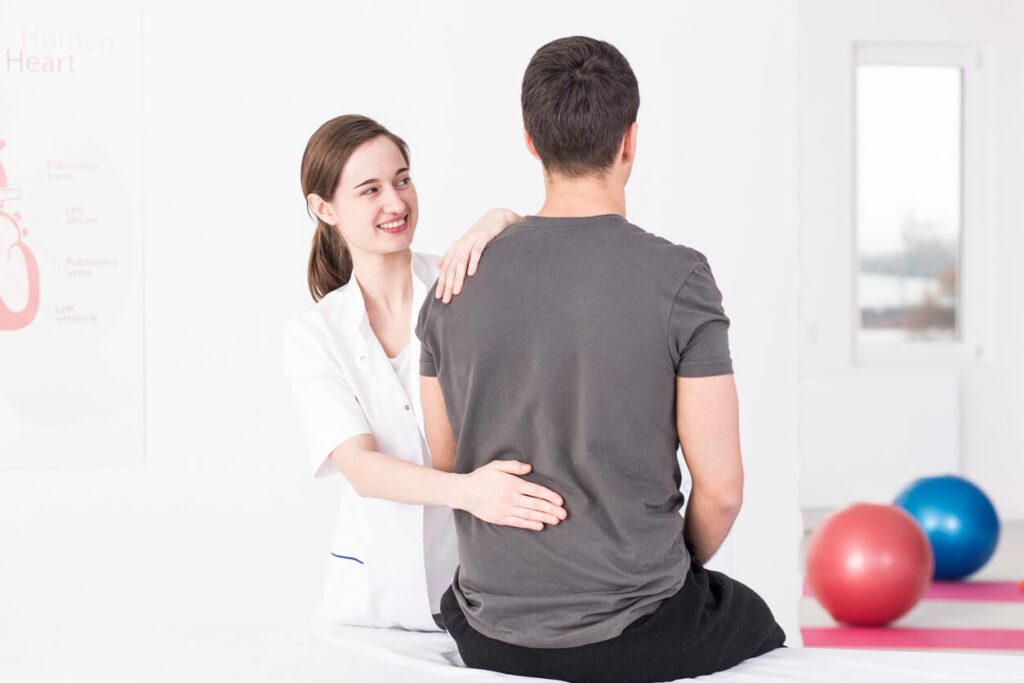 A female physical therapist is trying to locate the source of a patient's back and spine pain.