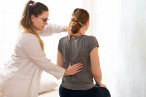 A female chiropractor is examining a female's patients back during her occupational health visit.